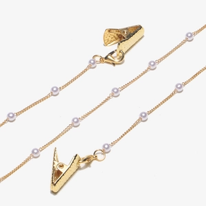 Detail of golden chain with white pearls and alligator clips for glasses or masks
