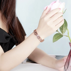 Rose gold mesh bracelet with infinity Love charm on wrist holding pink rose flower
