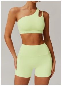 Detail of one-shoulder lime green sports top with cutout and high waist fitness shorts