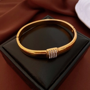 Detail of gold teardrop bangle featuring a pave square clasp set with sparkling crystals