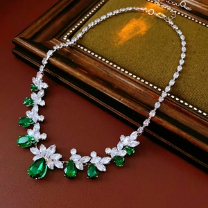 Détail du collier argenté avec gemmes en goutte vertes et blanches sur cadre en bois