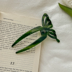 Detailed macro shot of a dark green acetate butterfly hair pin on an open book