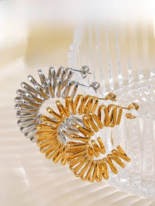 Macro shot of 18K gold and silver plated spiral C-hoop earrings on textured glass