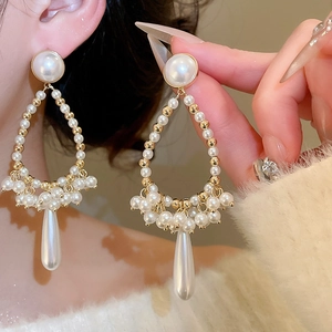 Macro detail of French retro pearl drop earrings with elegant gold beads and fringe