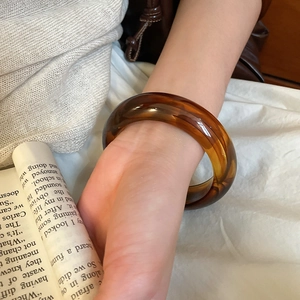 Detailed view of wide amber acrylic resin bangle with vintage tortoiseshell marble texture