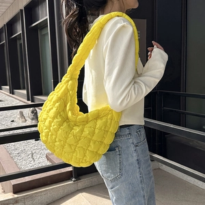 Bright yellow quilted cloud hobo bag in half-moon shape worn by model on shoulder