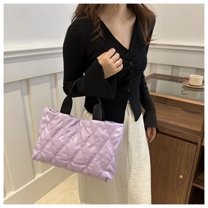 Detailed view of purple quilted tote bag with soft texture and black woven handles