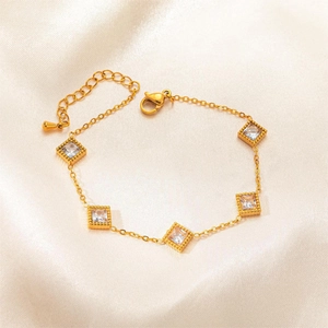 Detail of gold bracelet with five square clear zircons on elegant beige satin fabric