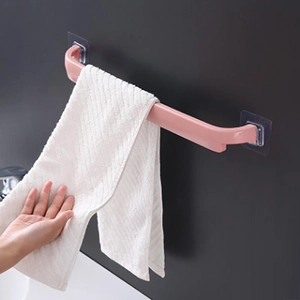 Wall-mounted pink bathroom towel rack with adhesive pads and white waffle towel