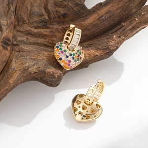 Golden heart drop earrings with colorful zircon stones on a rustic wooden background