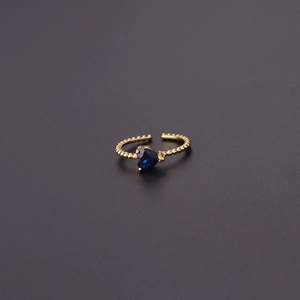 Detail of adjustable gold ring featuring a heart-shaped blue zircon and beaded band