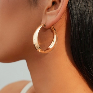 Close-up of minimalist large golden hoop earring worn on a model with polished finish
