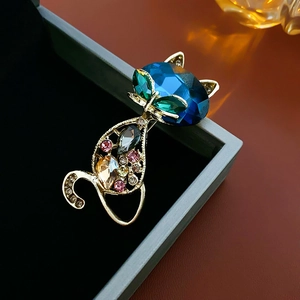 Macro detail of luxury gold hollow cat brooch with deep blue gem and vibrant rhinestones
