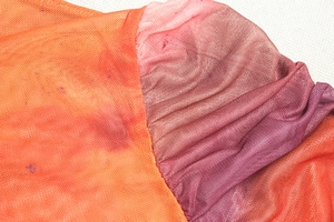 Detail of breathable mesh fabric showing gradient from orange to purple with soft pleats