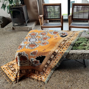 Close-up of bohemian orange knitted throw blanket with vintage floral patterns and tassels