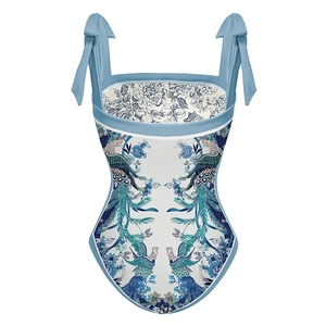 Detail of blue peacock floral print on white one-piece swimsuit with shoulder ties