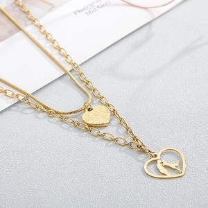 Detail of gold double-layered necklace with heart pendant and couple silhouette