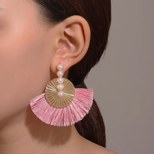 Macro detail of pink fan-shaped tassel earrings with golden metal and pearl accents
