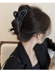 Gros plan d'une pince à cheveux noire mate en forme de cœur sur une femme