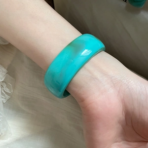 Close-up of translucent cyan resin bangle with internal texture on model wrist