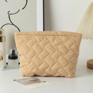 Detailed close-up of quilted beige makeup bag with premium stitching and soft texture