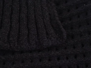 Macro della texture a maglia nera e dei dettagli a frange sul set maglione e gonna