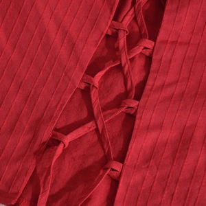 Dettaglio del tessuto rosso a coste con un intricato design di lacci incrociati