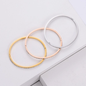 Three-color geometric titanium steel bangles with sparkling crystals on white marble