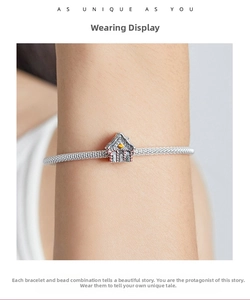 Macro view of S925 silver mesh bracelet with a colorful enamel house charm on a wrist