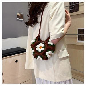 Detail of handmade crochet shoulder bag with 3D white daisy flowers and brown knit pattern