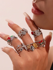 Macro view of gold plated rings featuring cherry, butterfly, and ladybug charms on hand