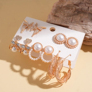 Detail view of gold earrings set with rhinestones and faux pearls on white card