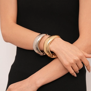 Polished chunky gold and silver metallic cuff bracelets shown on model wrist for a bold look