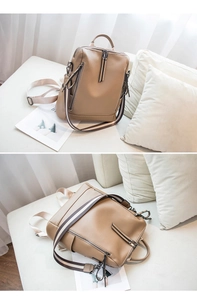 Detail view of khaki leather backpack with dual zippers and striped fabric shoulder straps