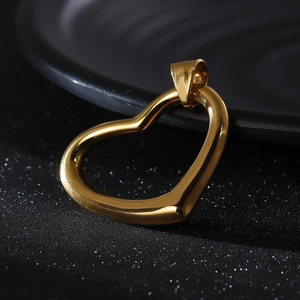 Close-up of a polished gold-plated heart pendant on a dark shimmering textured surface