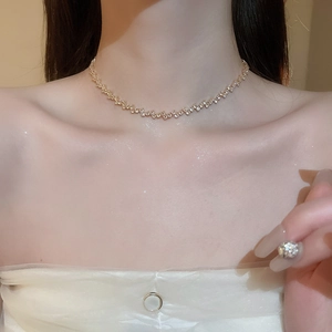 Detailed view of a gold zigzag necklace with sparkling cubic zirconia on a female model