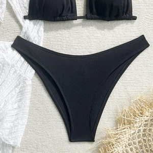 Flat lay of black ribbed bikini bottoms with lace beachwear and vacation decorations