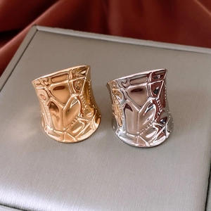 Macro detail of gold and silver geometric textured rings on a grey jewelry box