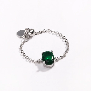 Detail of silver chain ring featuring an oval green zircon and heart charm pendant