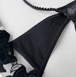 Detailed close-up of black velvet flower lace and ribbed cotton fabric on thong underwear