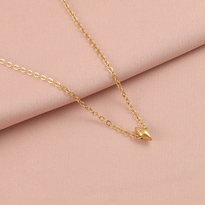 Detail view of a gold-tone seashell pendant necklace on soft pink textured fabric