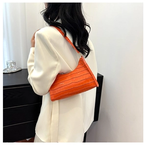 Detail view of the orange faux crocodile pattern on this stylish baguette shoulder bag