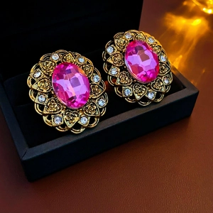 Detailed close-up of vintage gold earrings with pink center stones and clear rhinestones