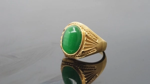 Detailed shot of a gold vintage ring with relief carving and a green oval cat-eye gemstone