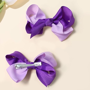 Detailed view of two-tone purple ribbon bow hair clips showing front and back metal structure