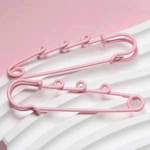 Close-up of pink 6cm lacquered safety pins with four-ring design on white striped base