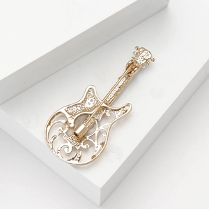 Macro detail of golden guitar brooch showing hollow patterns and pin closure
