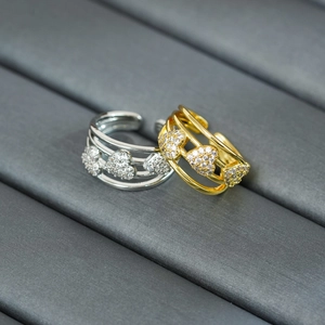 Close-up of 18k gold and silver adjustable rings with triple heart-shaped zircons