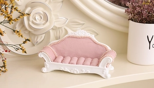 Detailed view of pink velvet sofa-style jewelry stand with white carved relief trim