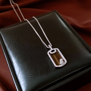 Gros plan du collier pendentif carré argenté avec pierre marron sur cuir noir